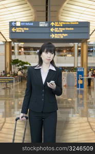 Businesswoman leaving an airport and holding a mobile phone
