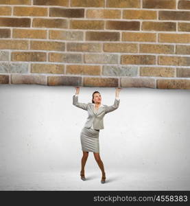 Businesswoman lifting brick wall. Image of businesswoman lifting brick wall above head