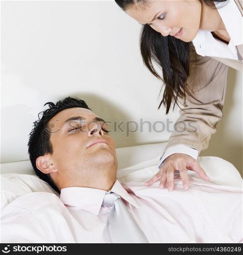 Businesswoman looking at a businessman sleeping in an armchair