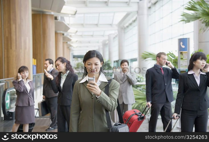 Businesswoman looking at a mobile phone and standing at an airport