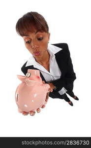 Businesswoman looking at a piggy bank