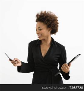Businesswoman looking at cellphone smiling against white background.