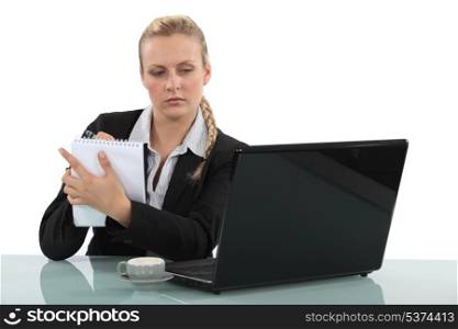businesswoman looking at her laptop and taking notes