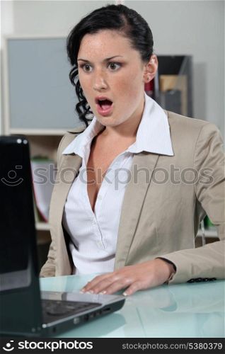 businesswoman looking at her laptop open mouthed