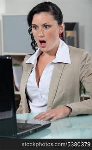 businesswoman looking at her laptop open mouthed