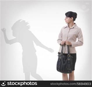 Businesswoman looking at shadow dancing against gray background