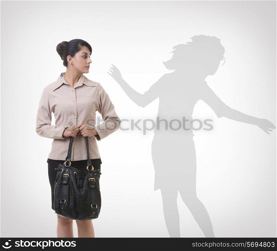 Businesswoman looking at shadow dancing over gray background