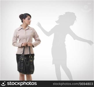 Businesswoman looking at shadow dancing over gray background