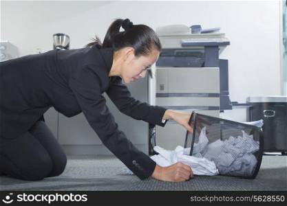 Businesswoman Looking for Papers in Trashcan