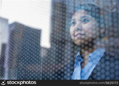 Businesswoman looking out through window, reflection of the city on the glass