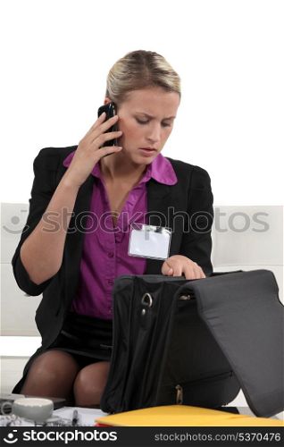 Businesswoman looking through briefcase whilst on the phone