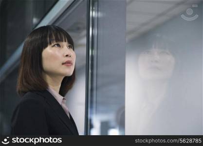 Businesswoman looking through glass, reflection, Beijing