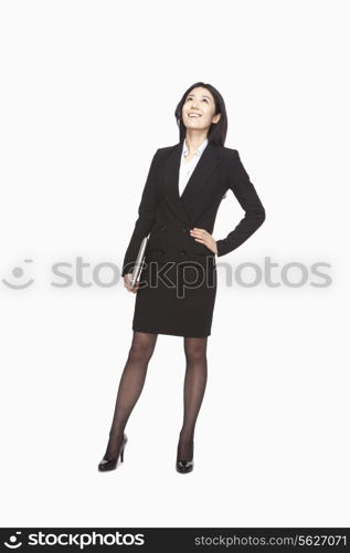 Businesswoman looking up with hand on hip