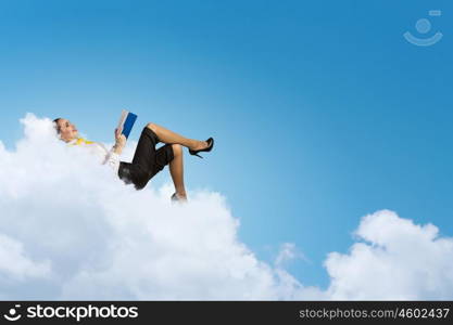 Businesswoman lying on clouds. Image of businesswoman lying on clouds with book