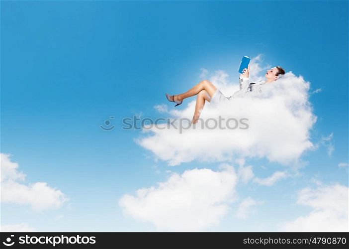 Businesswoman lying on clouds. Image of businesswoman lying on clouds with book