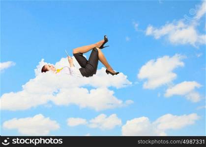 Businesswoman lying on clouds. Image of businesswoman lying on clouds with tablet pc