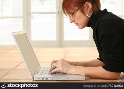 Businesswoman lying on the floor and working on a laptop