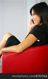 Businesswoman making call whilst sat in designer leather chair