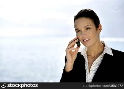 Businesswoman making phone call by the coast
