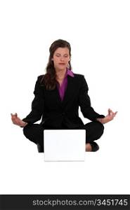 Businesswoman meditating in front of laptop