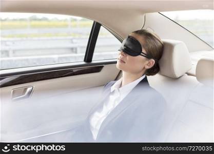 Businesswoman napping with mask in car during travel