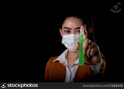 Businesswoman of young Asia woman putting on a respirator N95 mask with the hand that applying alcohol spray from the plastic bottle or anti bacteria to prevent the spread of germs at black background