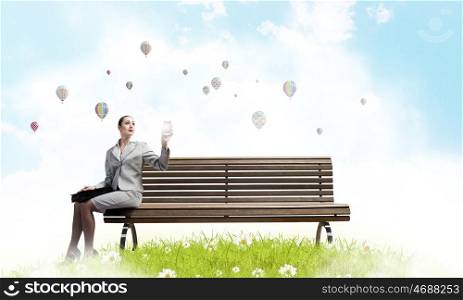 Businesswoman on bench. Young businesswoman with suitcase sitting on bench