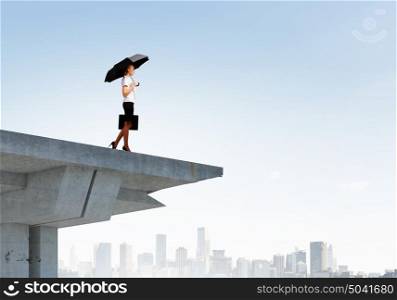 Businesswoman on bridge. Image of businesswoman standing at the edge of bridge. Risk concept
