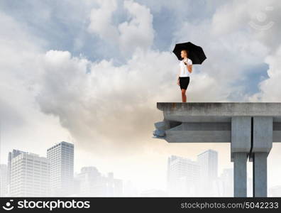 Businesswoman on bridge. Image of businesswoman standing at the edge of bridge. Risk concept