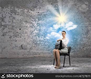 Businesswoman on chair. Image of young businesswoman sitting in chair holding suitcase
