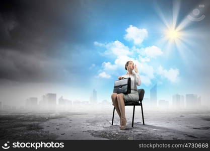 Businesswoman on chair. Image of young businesswoman sitting in chair holding suitcase