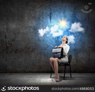 Businesswoman on chair. Image of young businesswoman sitting in chair holding suitcase