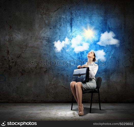 Businesswoman on chair. Image of young businesswoman sitting in chair holding suitcase