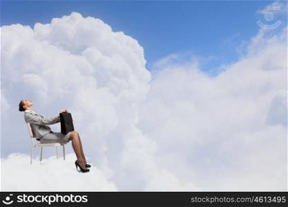 Businesswoman on cloud. Young businesswoman sitting on cloud high in sky