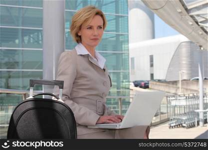Businesswoman on laptop outside airport