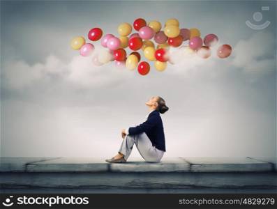 Businesswoman on roof. Young pretty businesswoman sitting on top of building with colorful balloons flying above