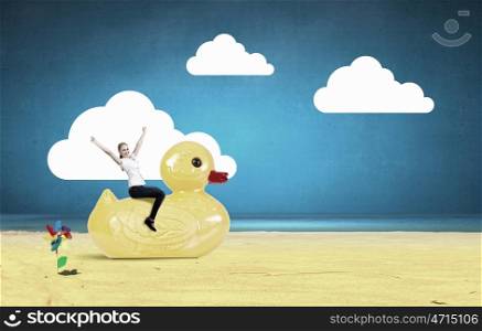 Businesswoman on rubber duck. Young happy businesswoman riding yellow rubber duck