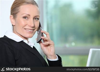 Businesswoman on the phone next to window.