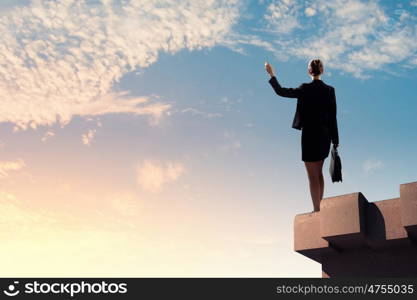 Businesswoman on top of building. Image of young businesswoman standing on top of building