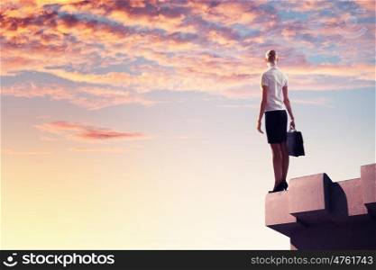 Businesswoman on top of building. Image of young businesswoman standing on top of building