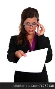 Businesswoman peering over her glasses and holding out a document