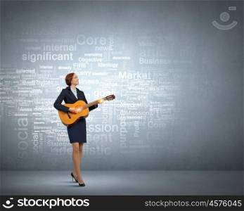Businesswoman playing acoustic guitar. Cheerful businesswoman playing acoustic guitar on color background