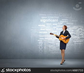 Businesswoman playing acoustic guitar. Cheerful businesswoman playing acoustic guitar on color background