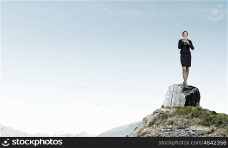 Businesswoman playing fife. Cheerful businesswoman standing on rock top and playing fife