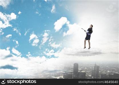 Businesswoman playing guitar. Cheerful businesswoman standing on cloud and playing electric guitar