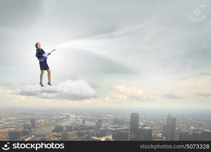 Businesswoman playing guitar. Cheerful businesswoman standing on cloud and playing electric guitar