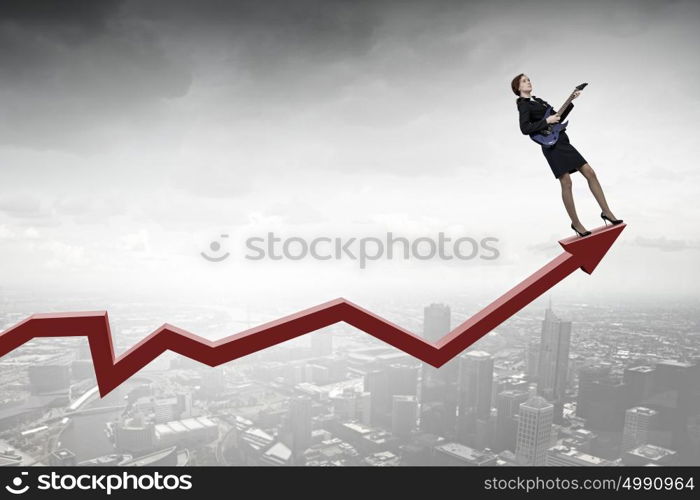 Businesswoman playing guitar. Cheerful businesswoman standing on graph and playing electric guitar