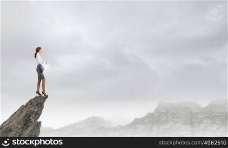 Businesswoman playing guitar. Cheerful businesswoman standing on rock edge and playing electric guitar