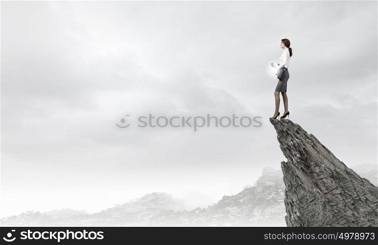 Businesswoman playing guitar. Cheerful businesswoman standing on rock edge and playing electric guitar