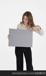 Businesswoman pointing at a blank placard